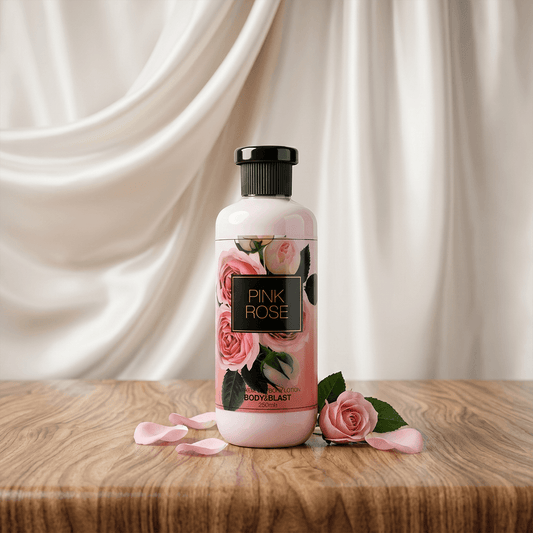 Bottle of Pink Rose body wash with roses and petals on a wooden surface and draped fabric background