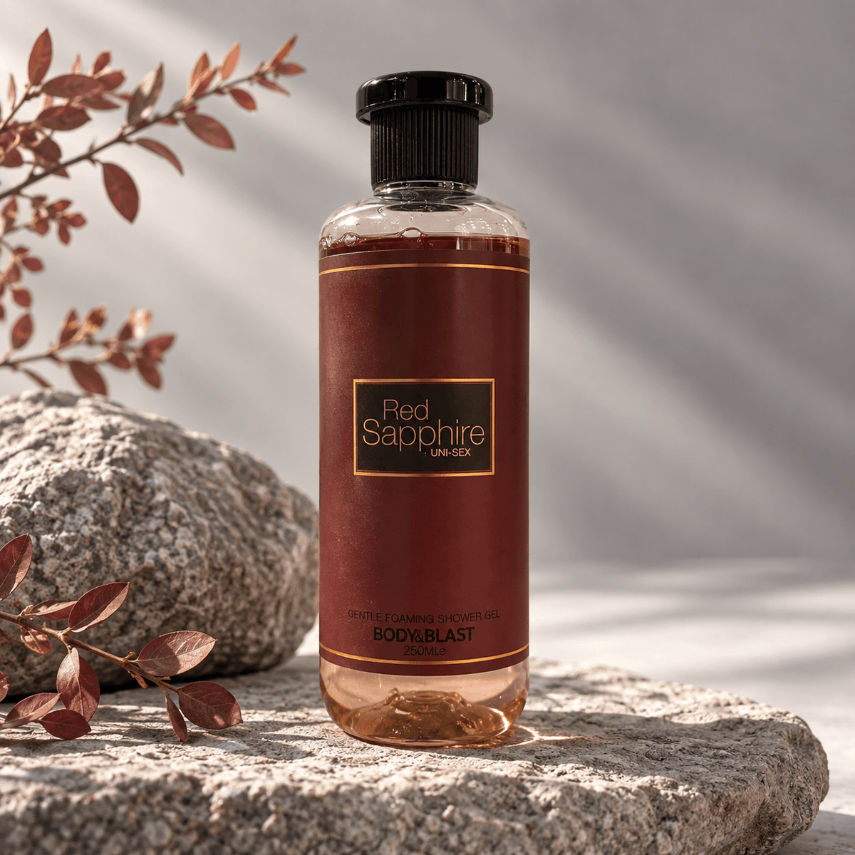 Bottle of Red Sapphire body wash on a decorative stone surface with greenery and flowers.